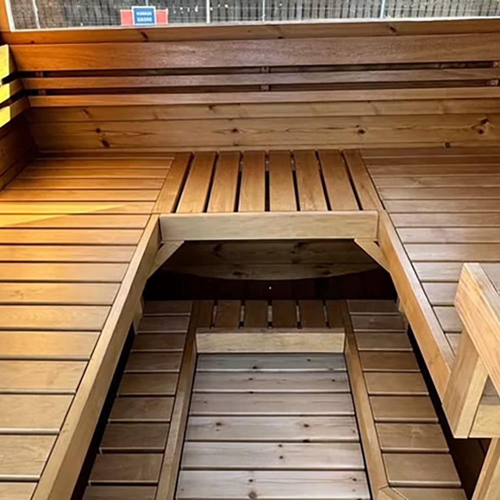Bench Warm wooden sauna interior with tiered benches and a square opening leading to a lower level.